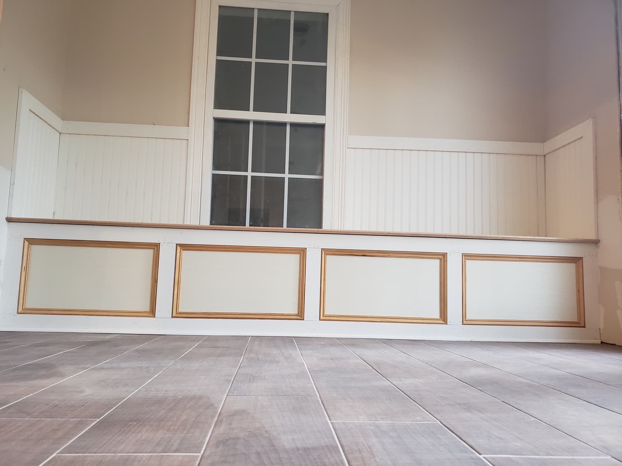 Finished beadboard wainscoting with a chair rail and recessed panel base, above a grey wood-look tile floor