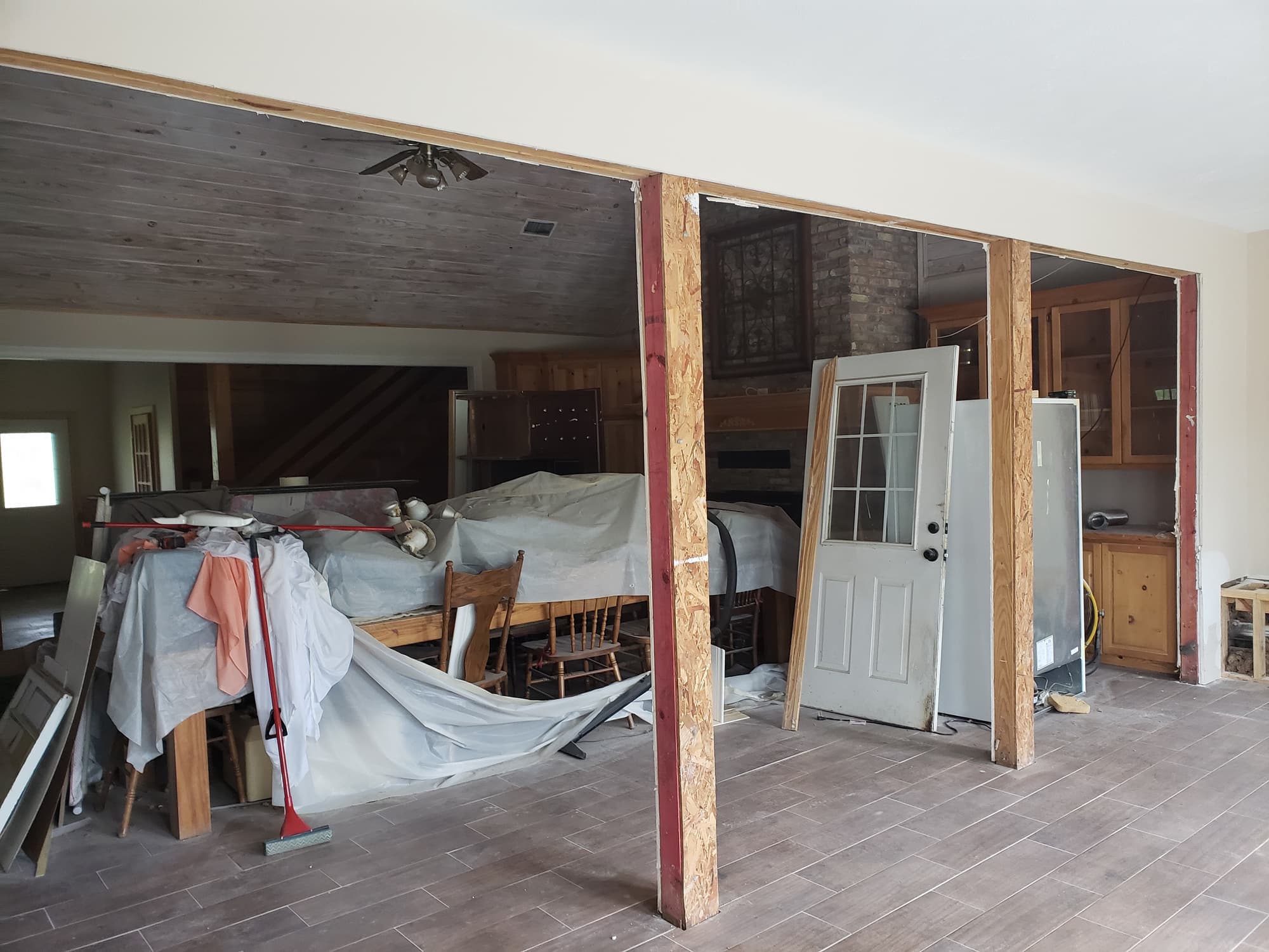 A load-bearing wall opened between a kitchen and living room, with temporary posts and a new header carrying the span